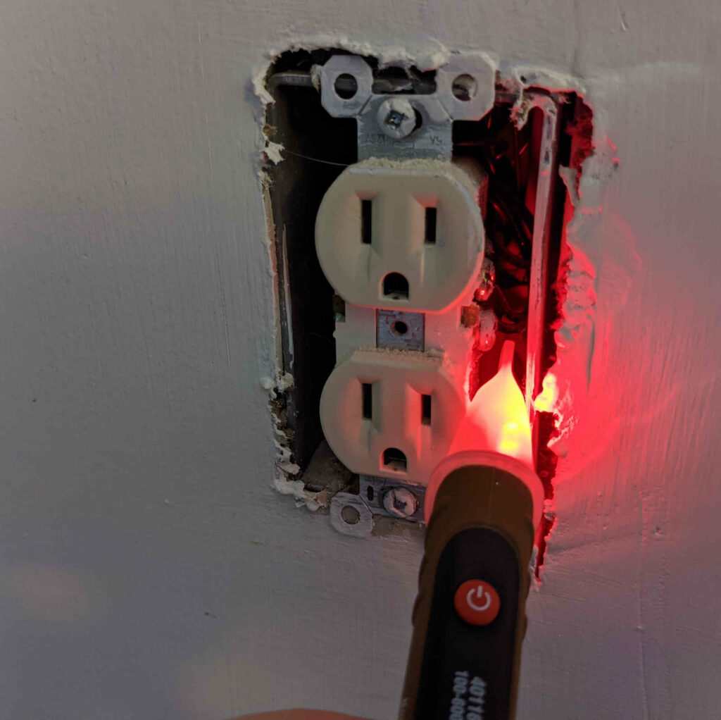 Volt Tester testing live wire connectors on outlet - Paint Covered Overalls